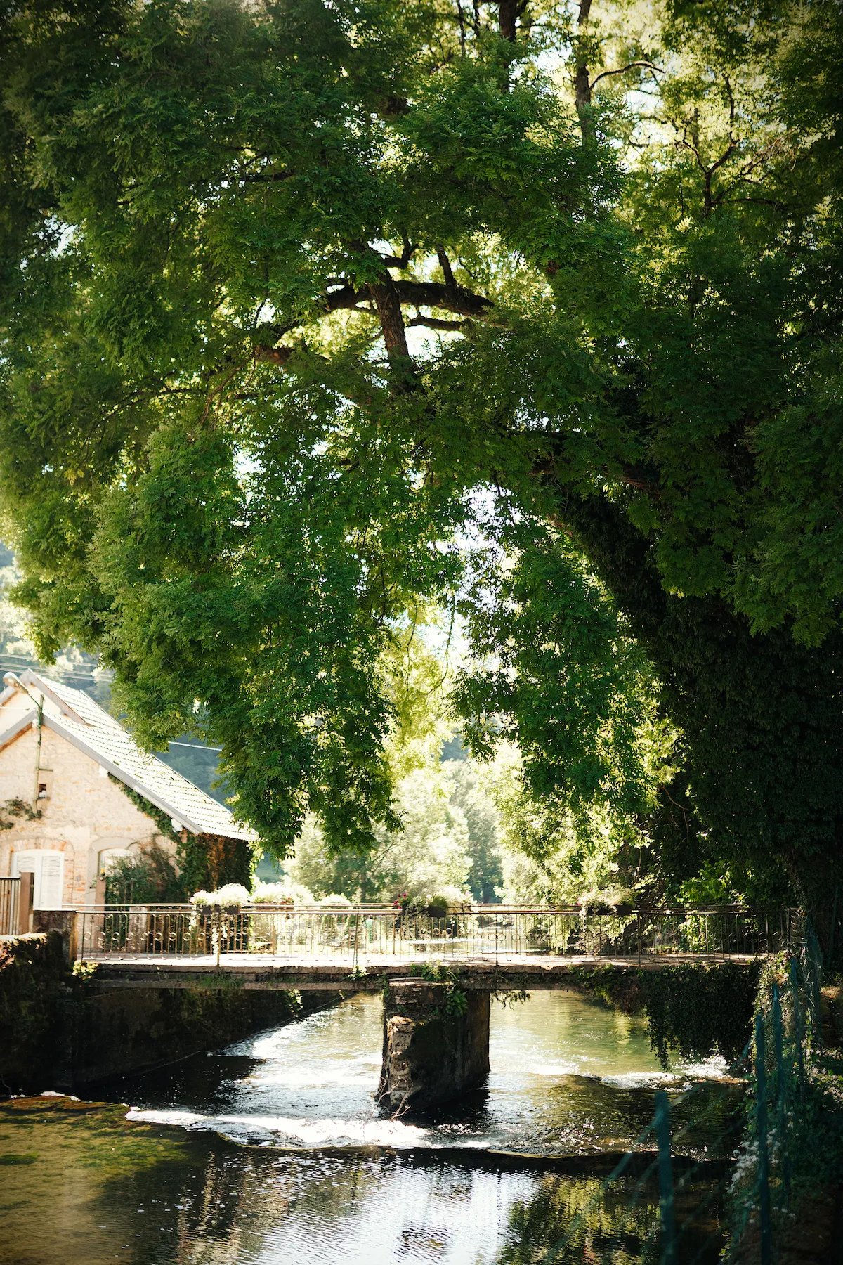 Vue bucolique du Domaine des Bains de Guillon, entre pont de pierre et ruisseau, cadre idéal pour un mariage