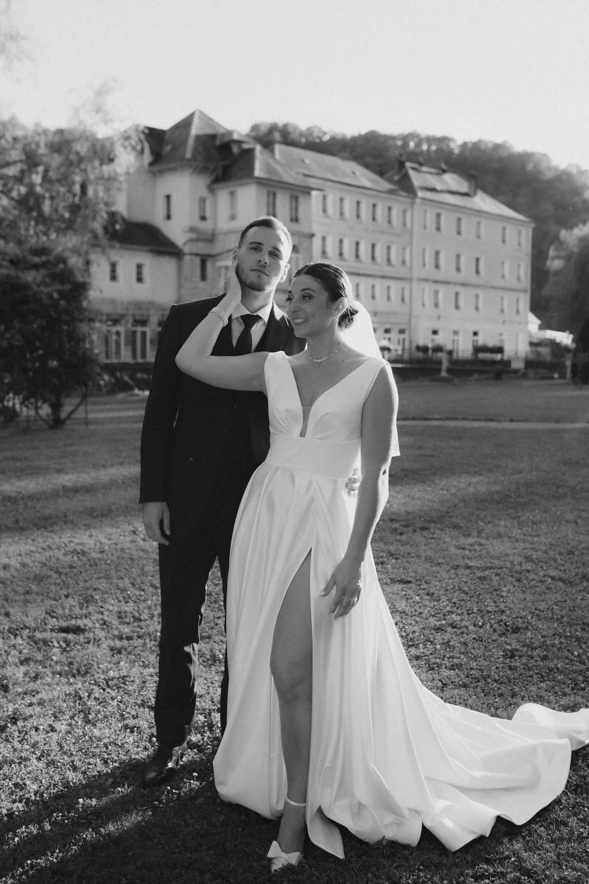 Les mariés posent devant le Domaine des Bains de Guillon dans un moment complice et romantique