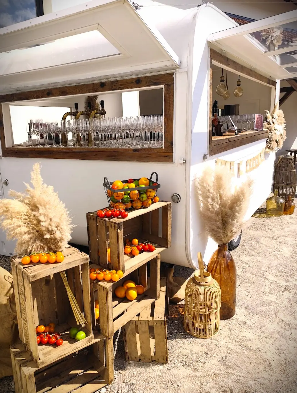 Caravane vintage Louise Nomad Bar décorée de caisses en bois, légumes et pampas pour un mariage bohème.
