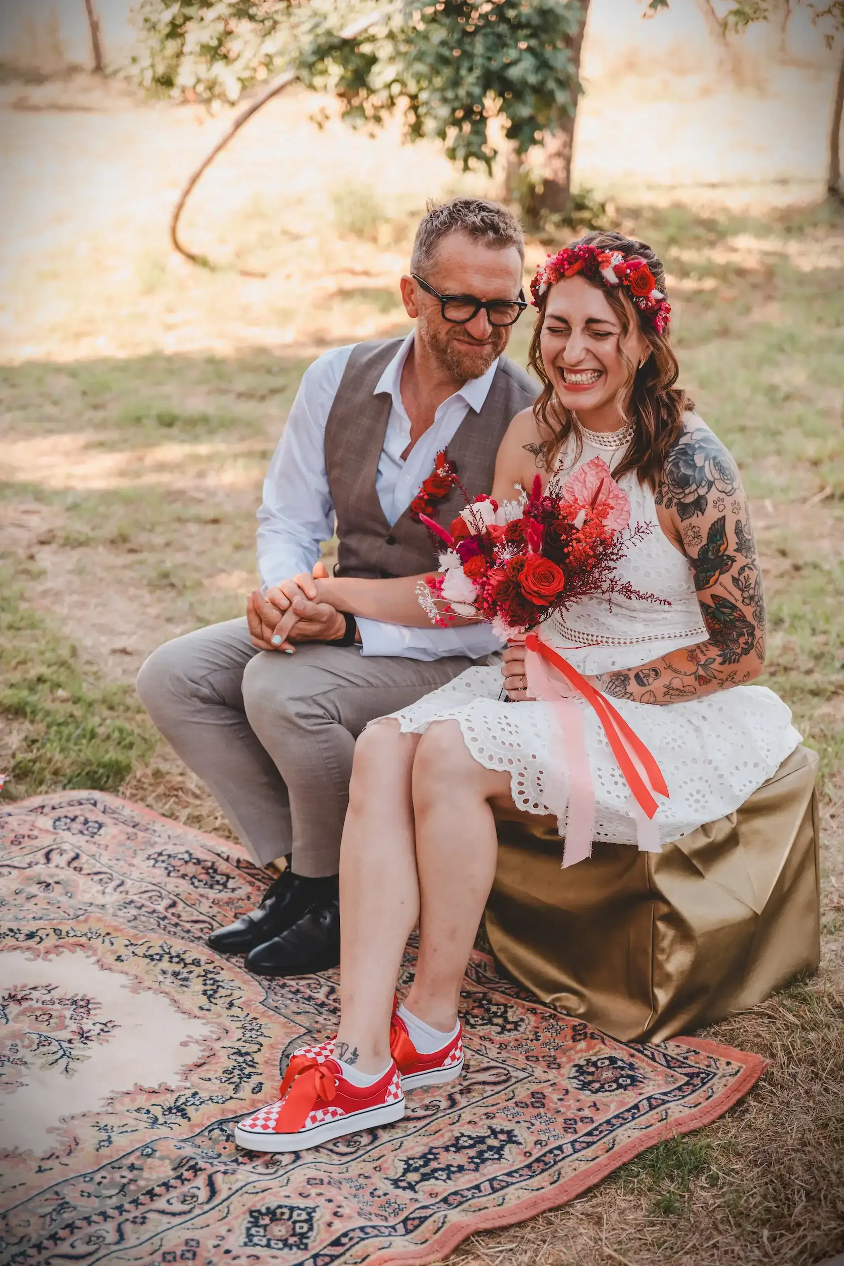 Couple de mariés bohème assis sur tapis lors du shooting Wild in Love fête foraine
