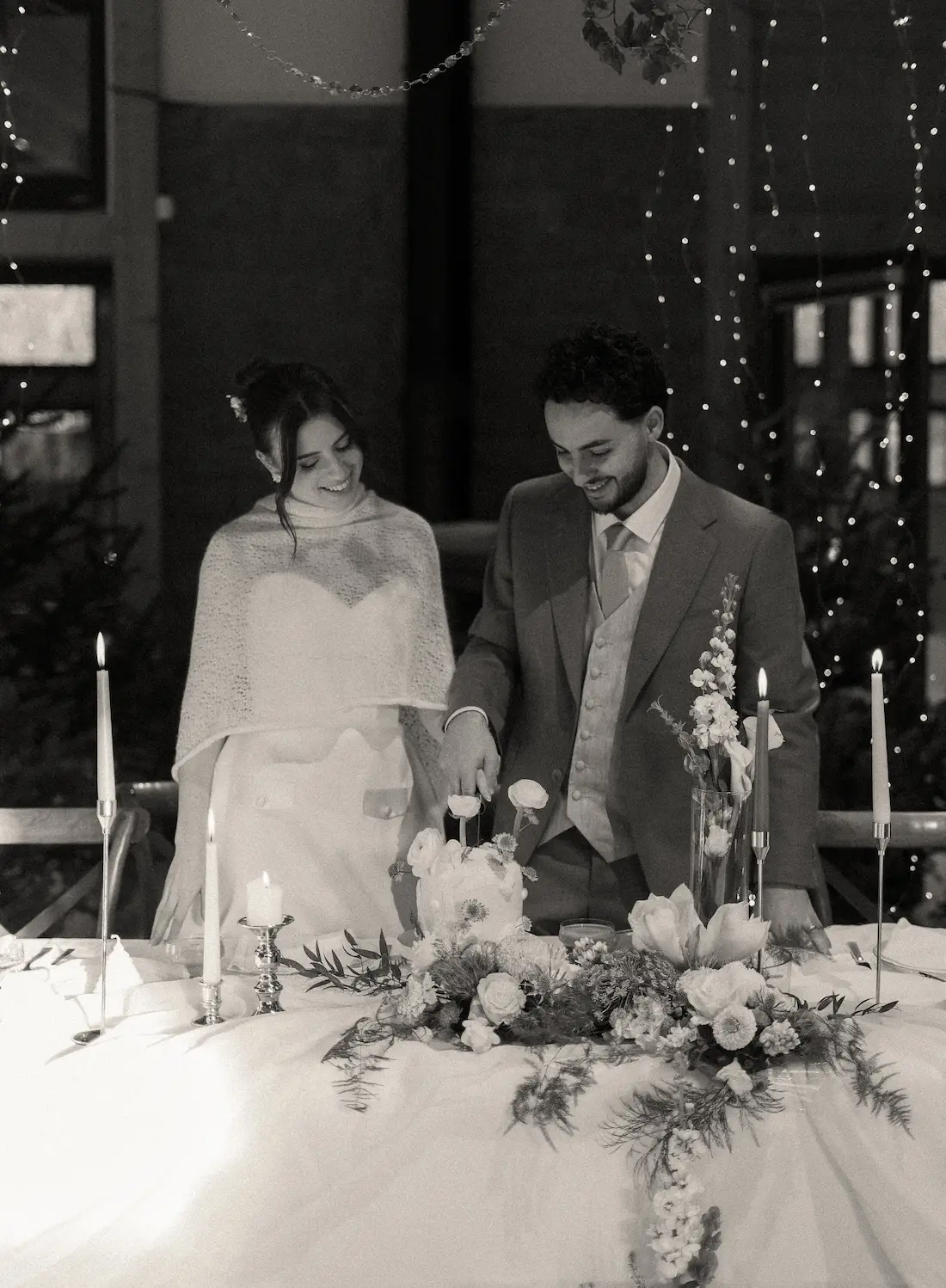 Couple de mariés en noir et blanc devant une table décorée pour un mariage hivernal au Domaine du Hirtz