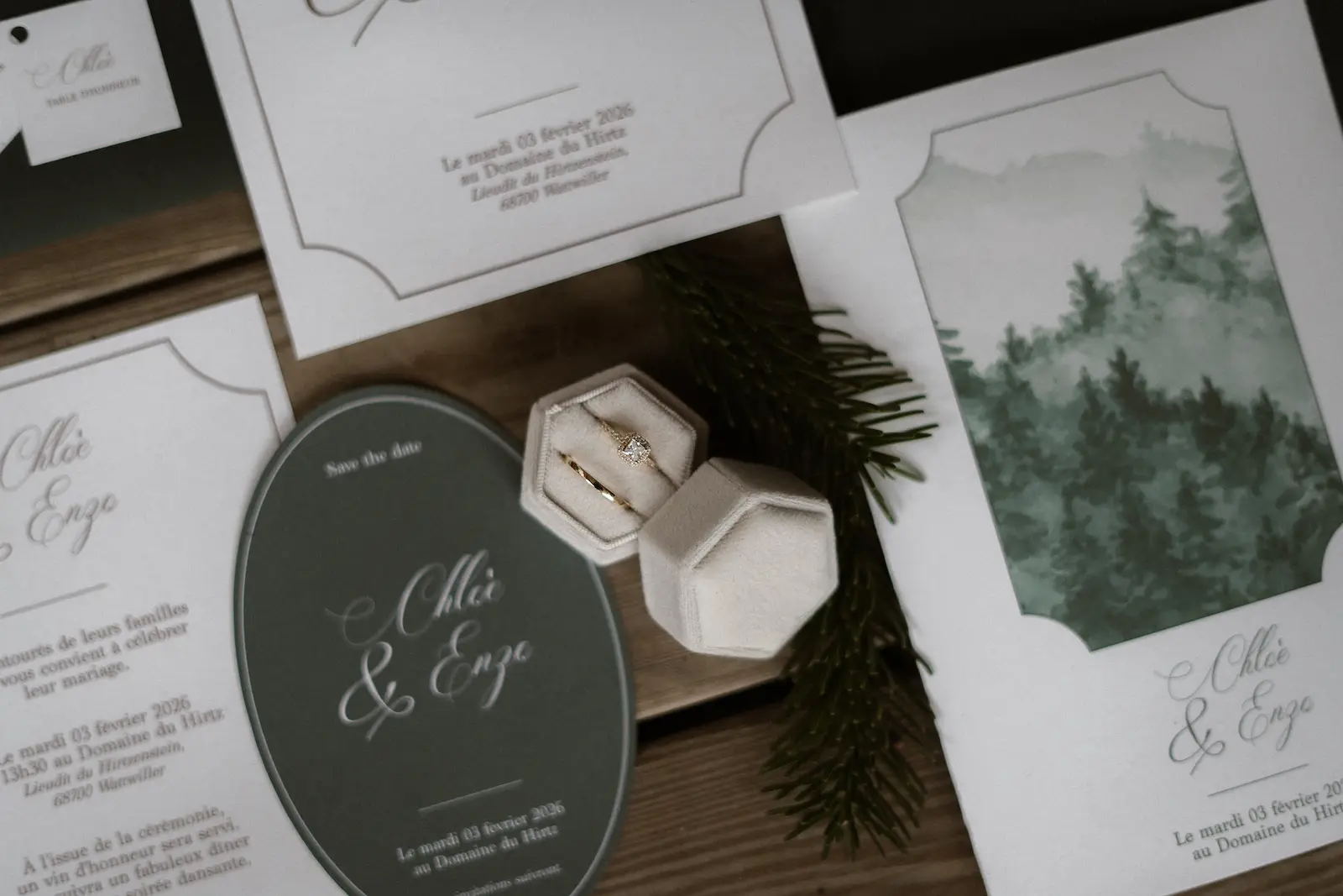 Gros plan sur une papeterie de mariage aux tons verts et blancs avec alliance et faire-part